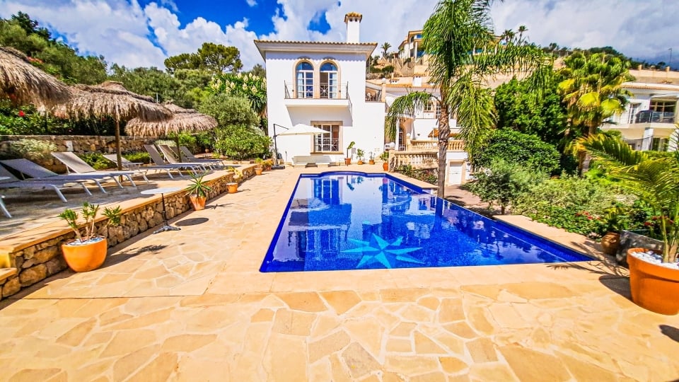 Mediterrane Villa mit blau gefliestem Pool, Terrakotta-Außenbereich und üppiger Gartenbepflanzung.