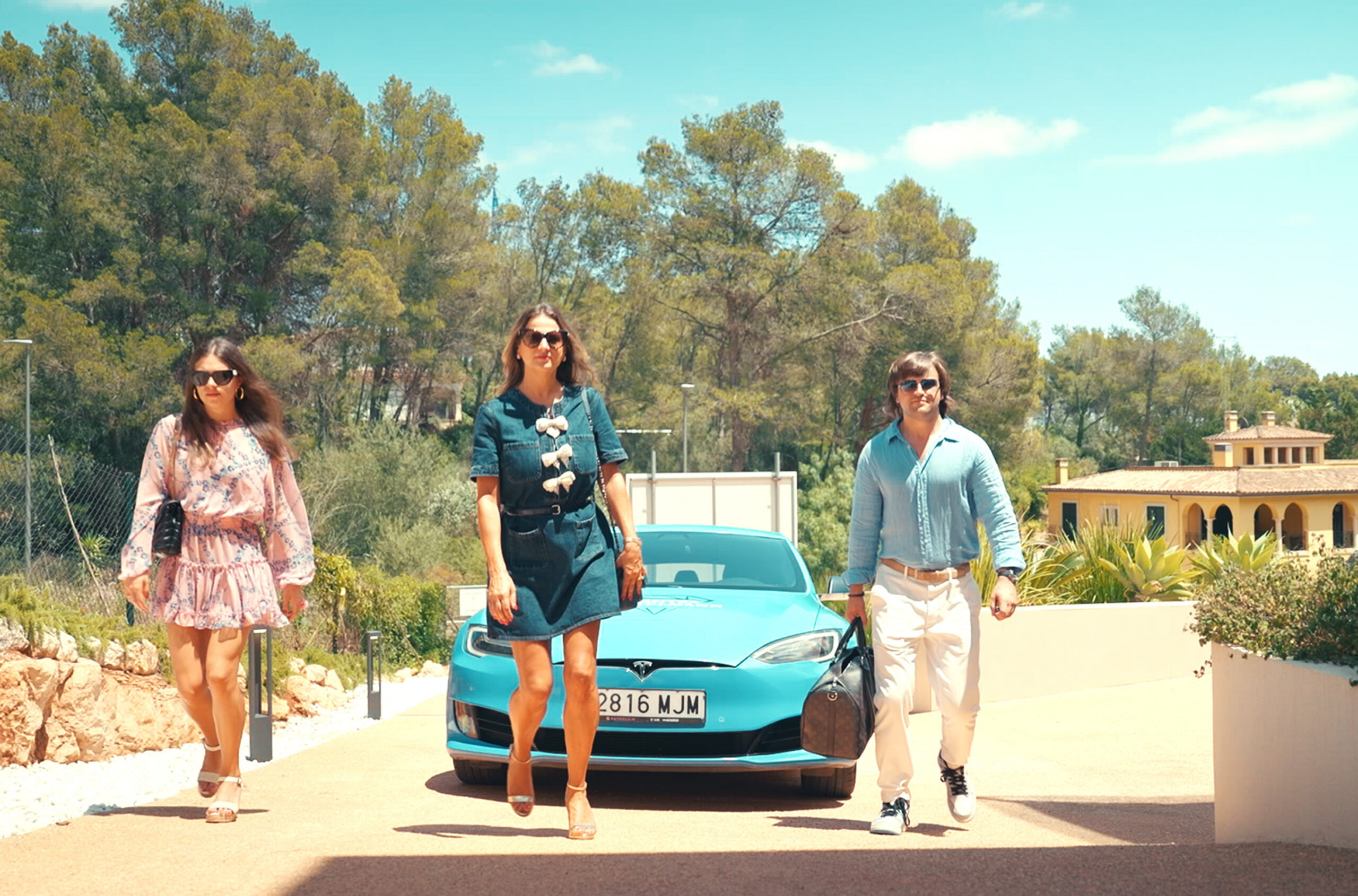 Rossitza und ihre beiden Kinder vor einem türkisfarbenen Auto, umgeben von mediterranen Bäumen.