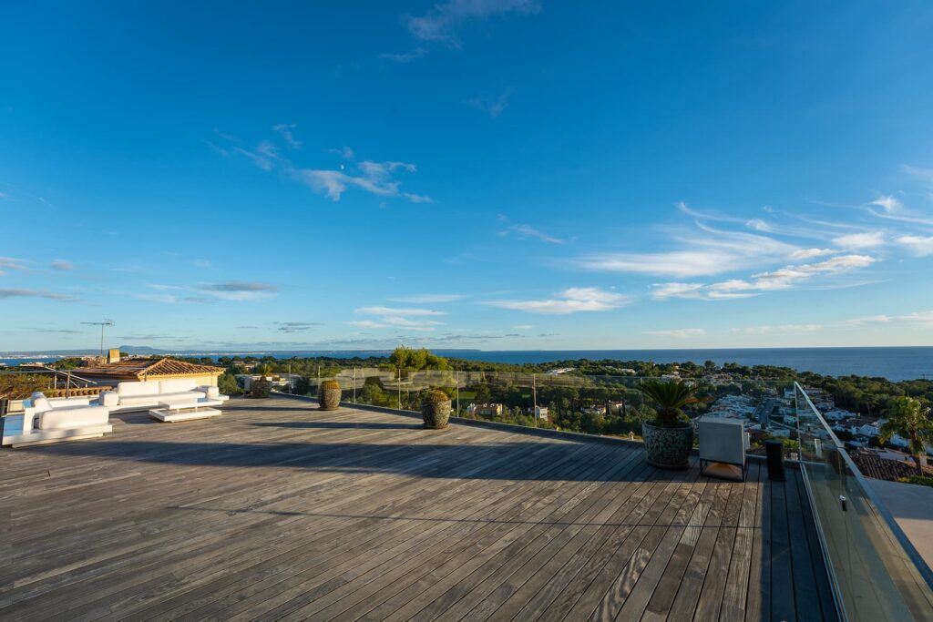 Roof terrace with wooden deck and panoramic views of a coastal landscape.