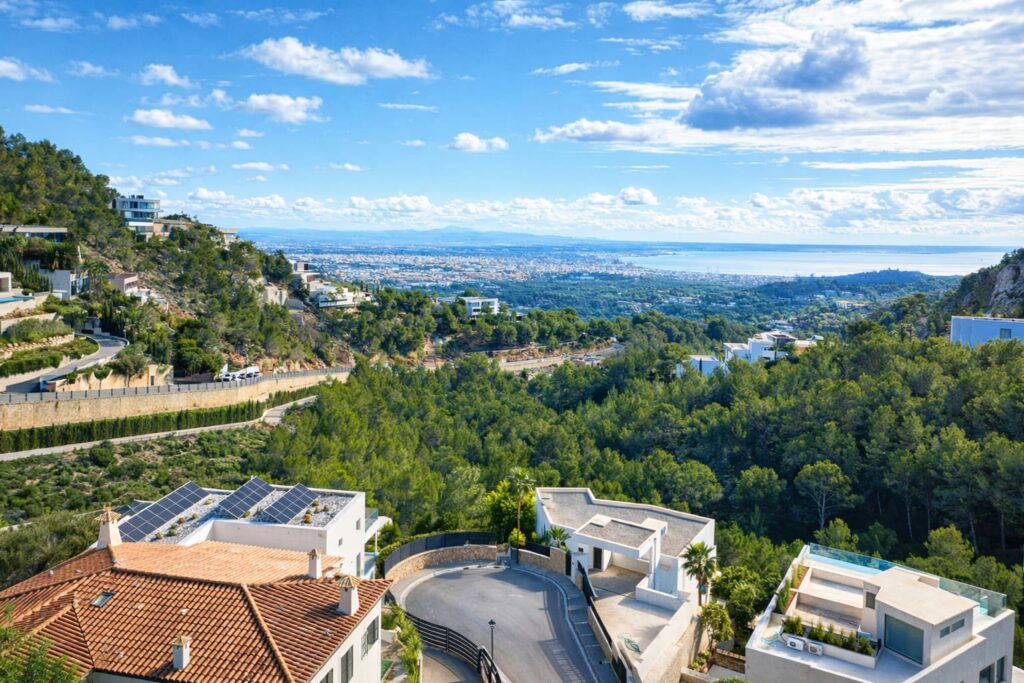 Zona residencial en pendiente con edificios modernos, rodeada de bosque, con vistas amplias a Palma
