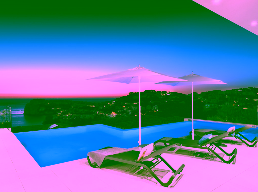 Piscina infinita con tumbonas y dos sombrillas blancas en la terraza con vistas al paisaje costero al atardecer.