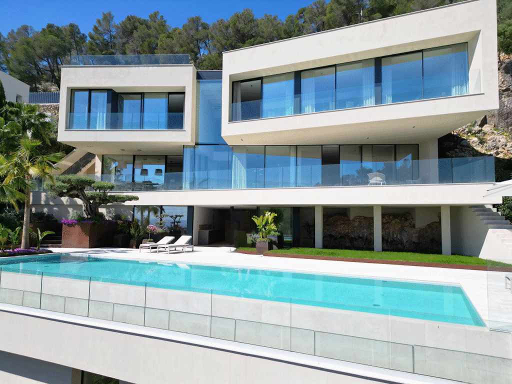 Moderna villa de varios pisos con grandes ventanales, balcón y piscina larga en primer plano