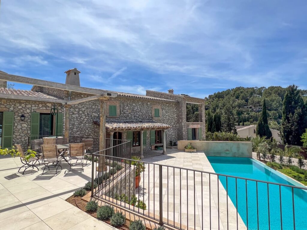 Finca de alta calidad con fachada de piedra natural, contraventanas y terraza con piscina con amplias vistas al campo.
