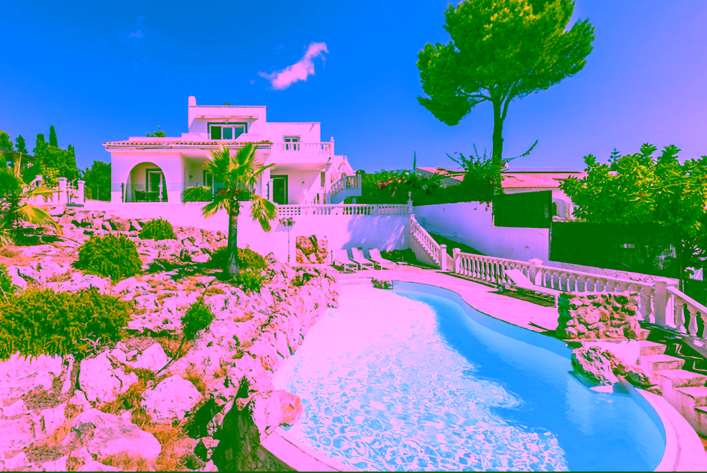 White villa with curved pool and rocky landscape.